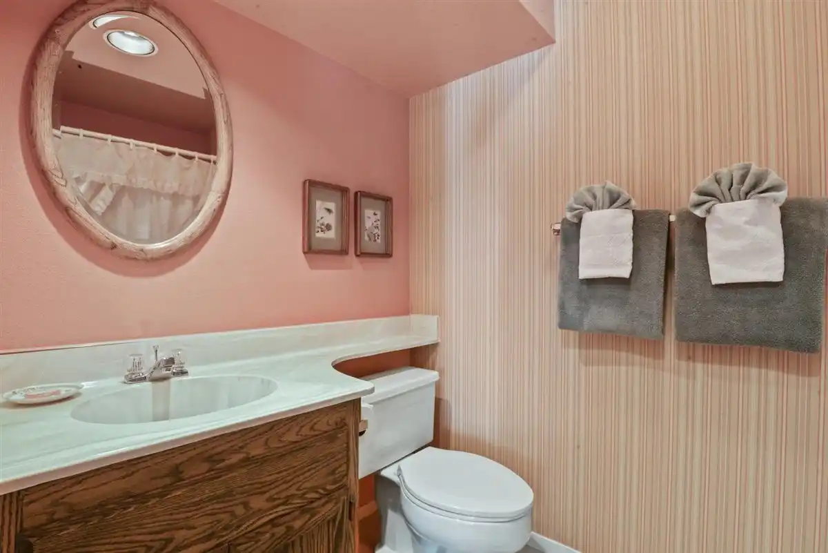 A vintage wood framed oval mirror above a sink, next to two plush gray towels.